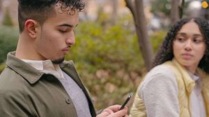 Un homme consulte les messages sur son portable, sa femme triste et jalouse : guide, conseils et exercices pour ne plus être jalouse