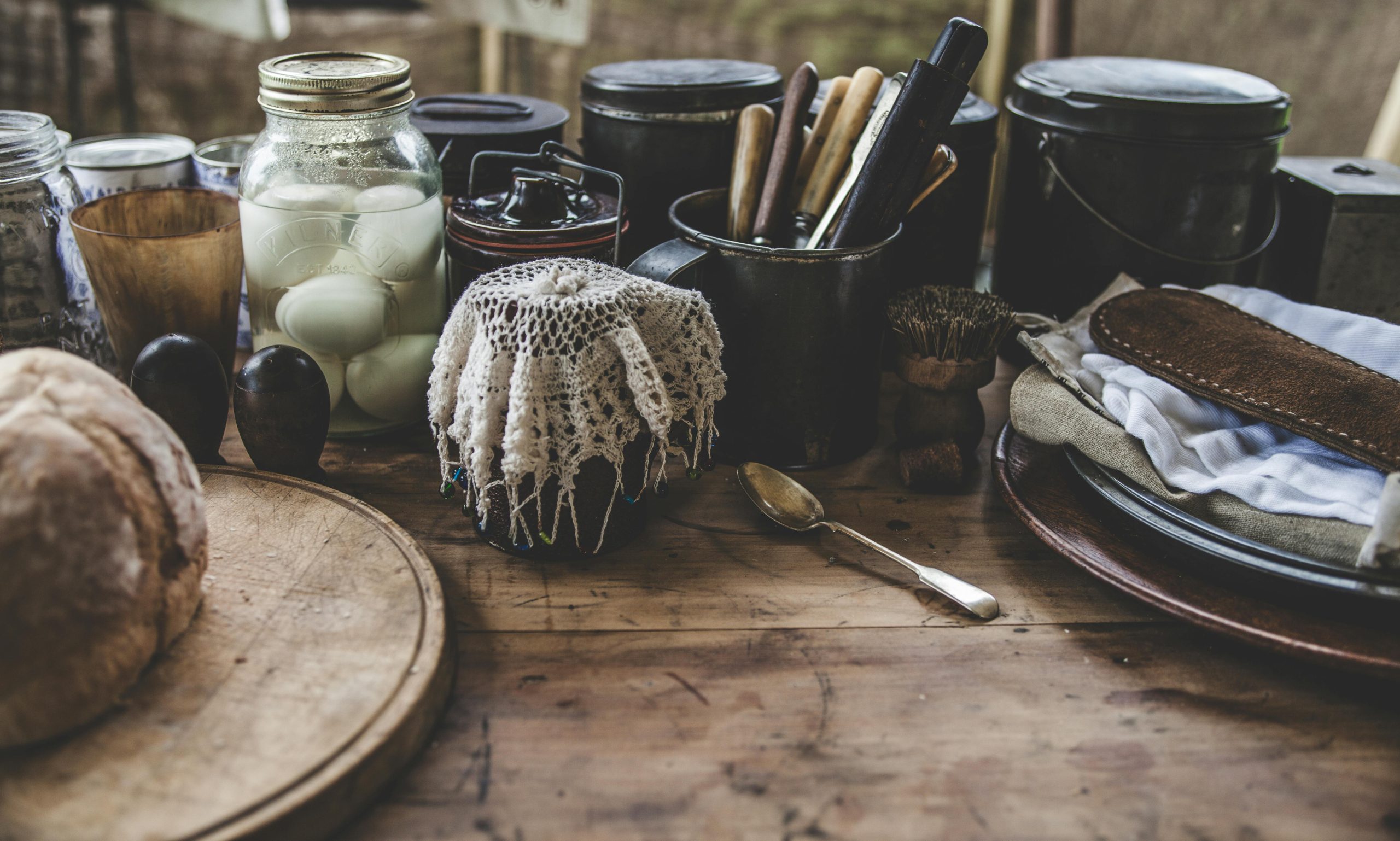 A rustic kitchen scene featuring pickled eggs, bread, and kitchenware on a wooden table. Une scène de cuisine rustique mettant en vedette des œufs marinés, du pain et des ustensiles sur une table en bois.