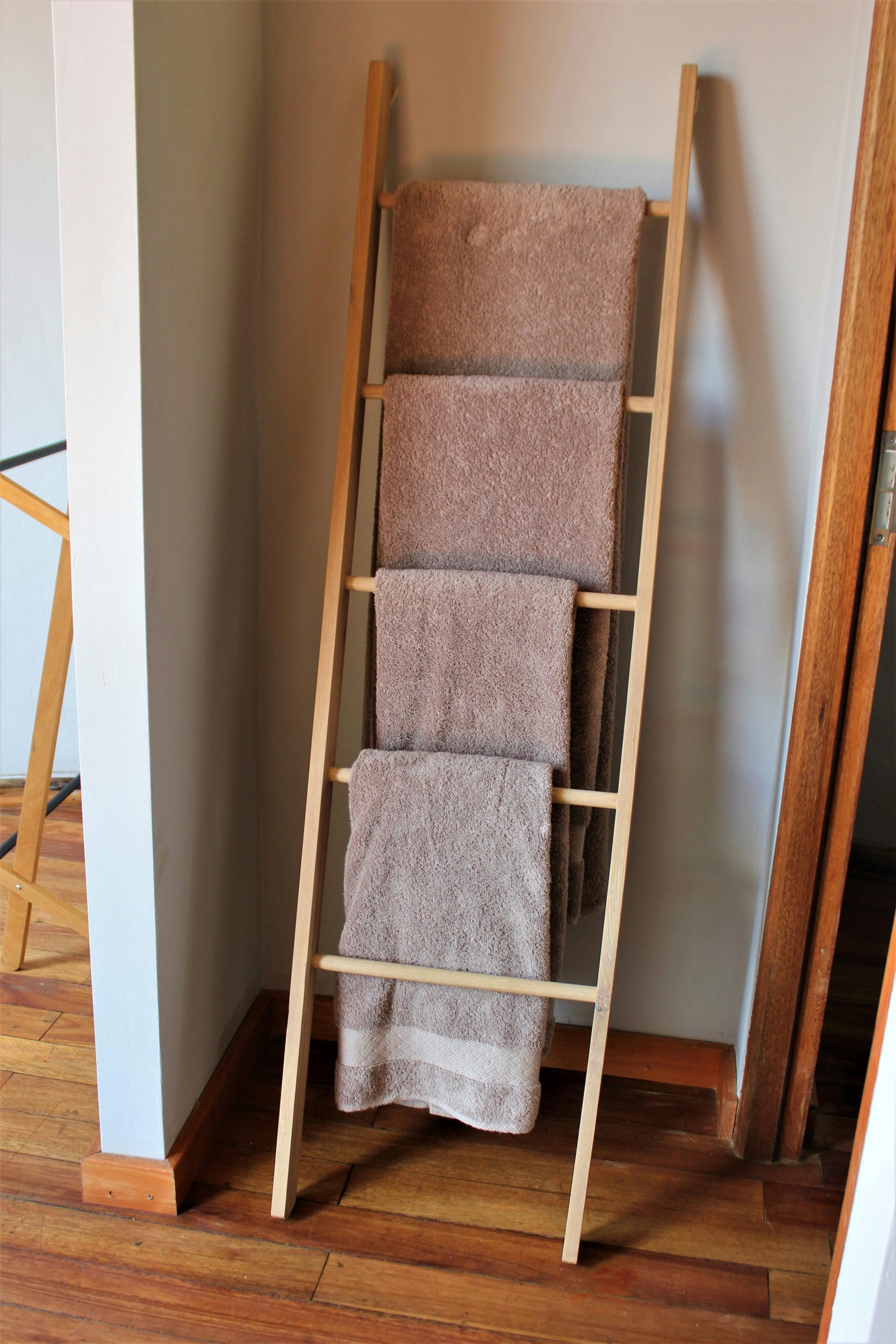 Porte-serviettes en bois simple avec des serviettes bien accrochées dans un cadre domestique moderne et minimaliste.