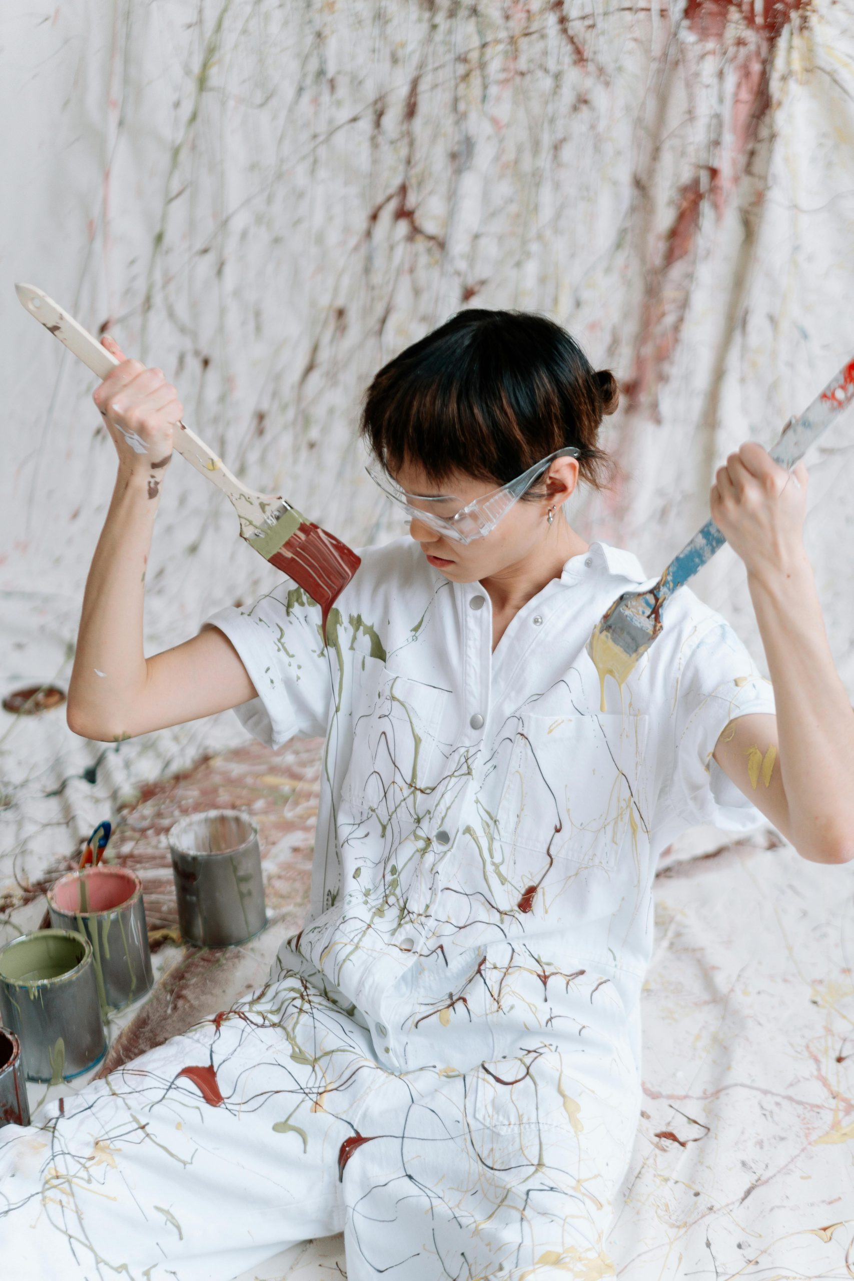Un artiste en action projetant de la peinture avec des pinceaux, entouré de couleurs vibrantes.