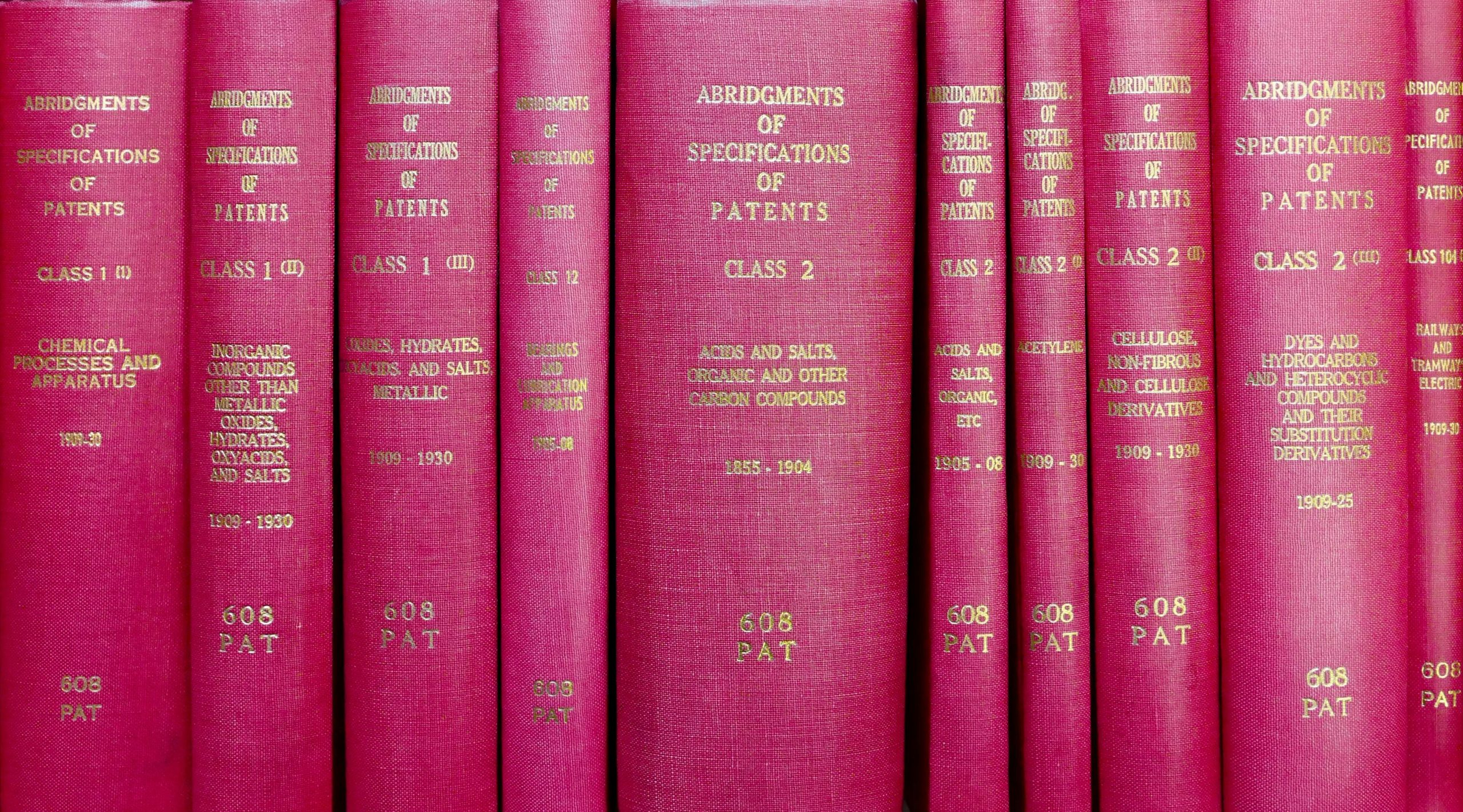 A row of red hardcover books titled 'Abridgments of Specifications of Patents'. Une rangée de livres cartonnés rouges intitulés « Abrégés des spécifications des brevets ».
