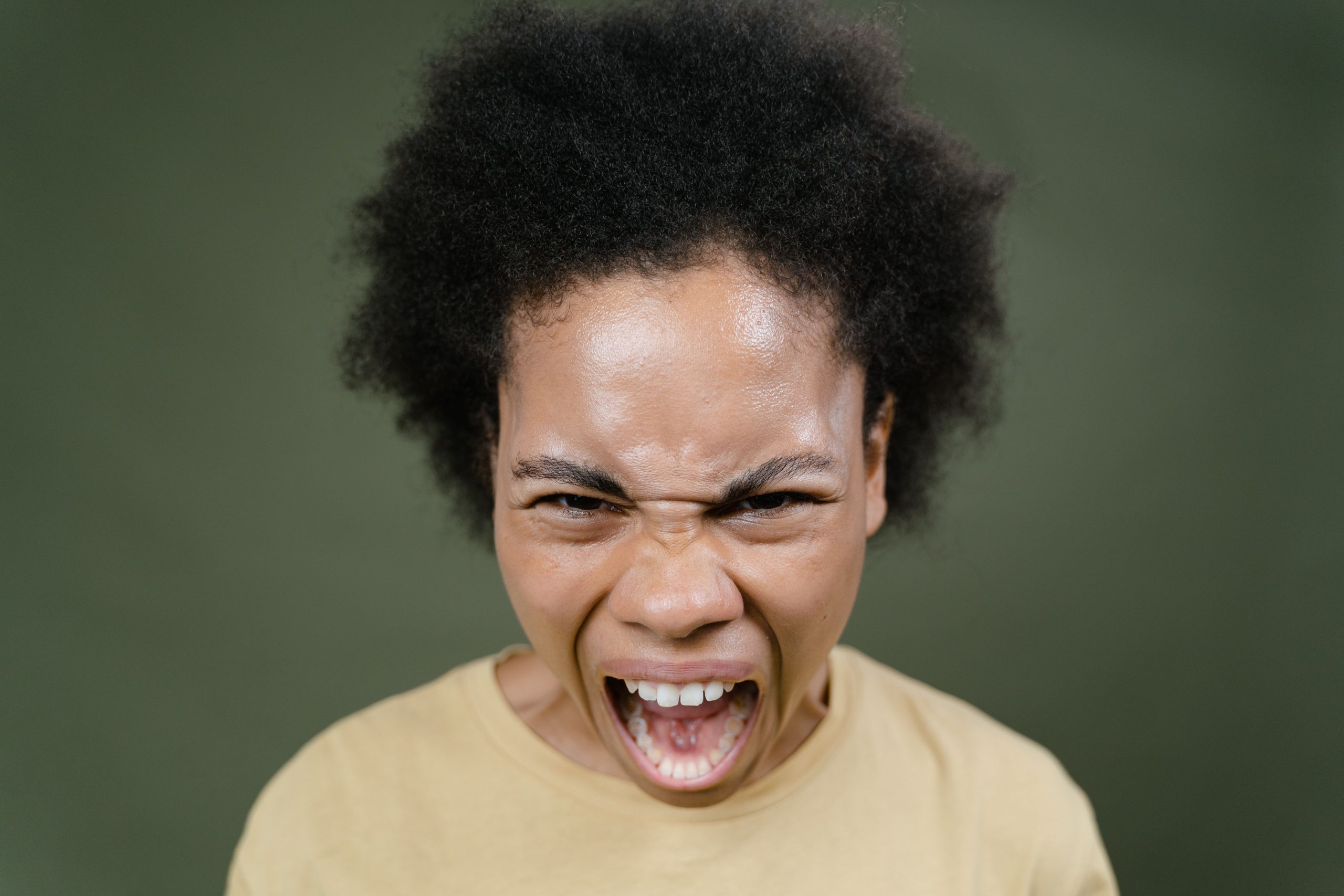 Close-up of an African American woman with afro hair expressing anger in a studio setting. Gros plan d'une femme afro-américaine aux cheveux afro exprimant sa colère dans un cadre de studio.