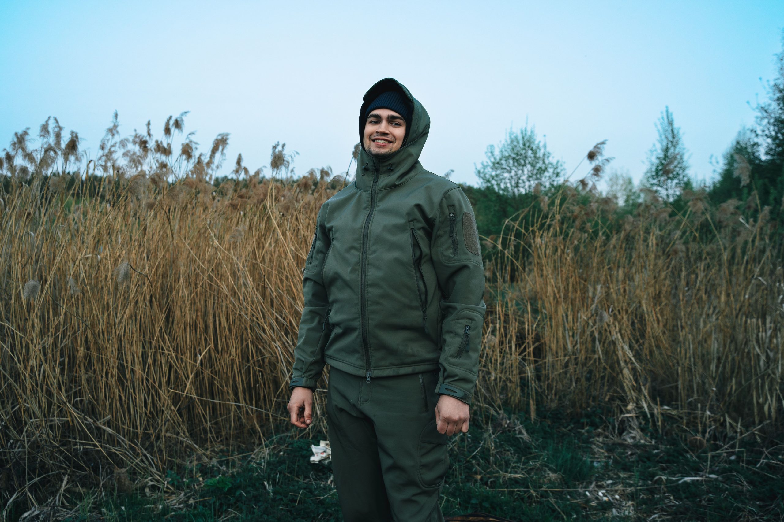 Homme sourirant dans une veste verte debout dans un champ en Biélorussie.